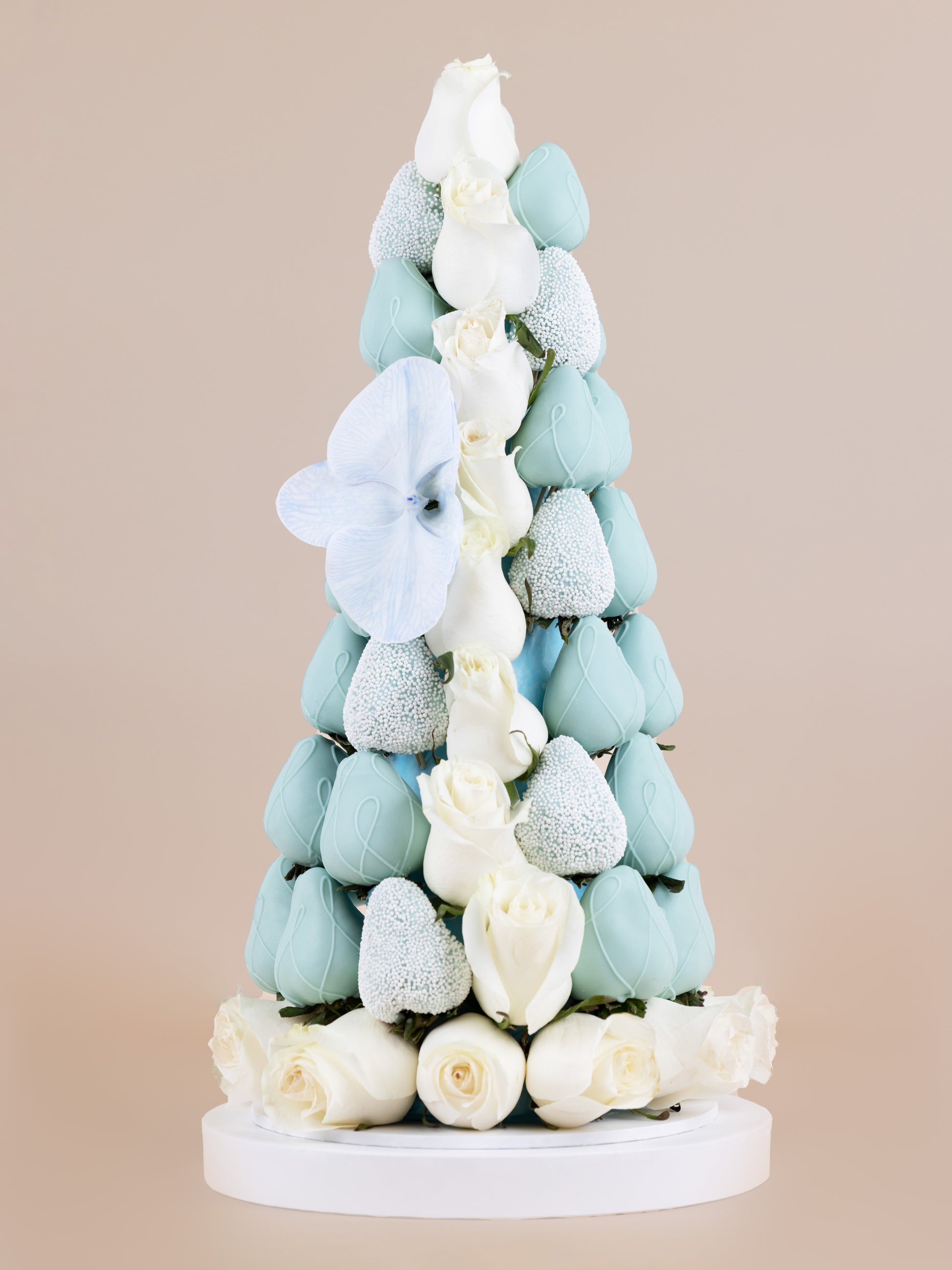 Tower made of baby blue, chocolate dipped strawberries with white Colombian roses placed within and at the base of the tower and an orchid