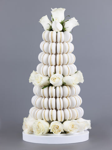 A tower made of white coloured, handmade macarons with fresh, white Colombian roses placed within the tower