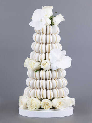 A tower made of white coloured, handmade macarons with orchids and fresh, white Colombian roses placed within the tower